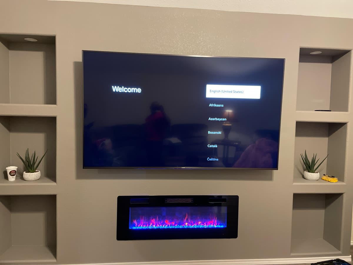 Custom built-in entertainment center with TV mounted above electric fireplace by Cognito Media Services in Dallas TX