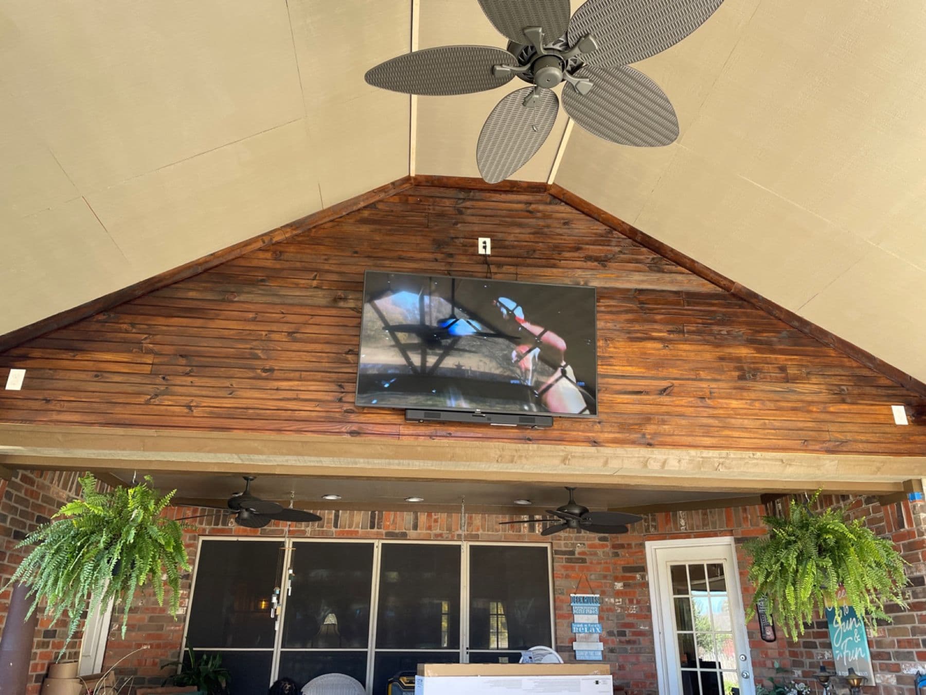 Patio TV and speakers mounted on a rustic wood gable in DFW